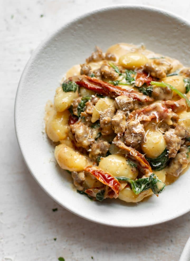 close-up in a white bowl of sausage gnocchi with Tuscan cream sauce