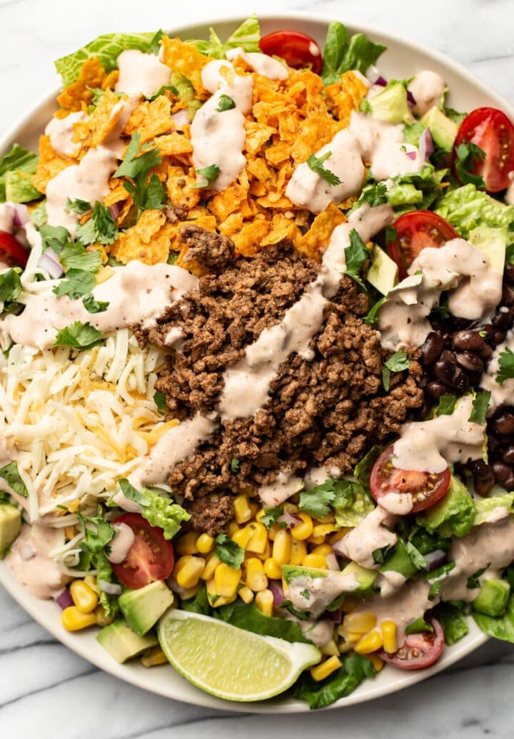 a bowl of beef taco salad with a lime wedge