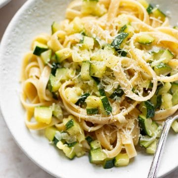 zucchini pasta in a white bowl with fettuccine and a fork