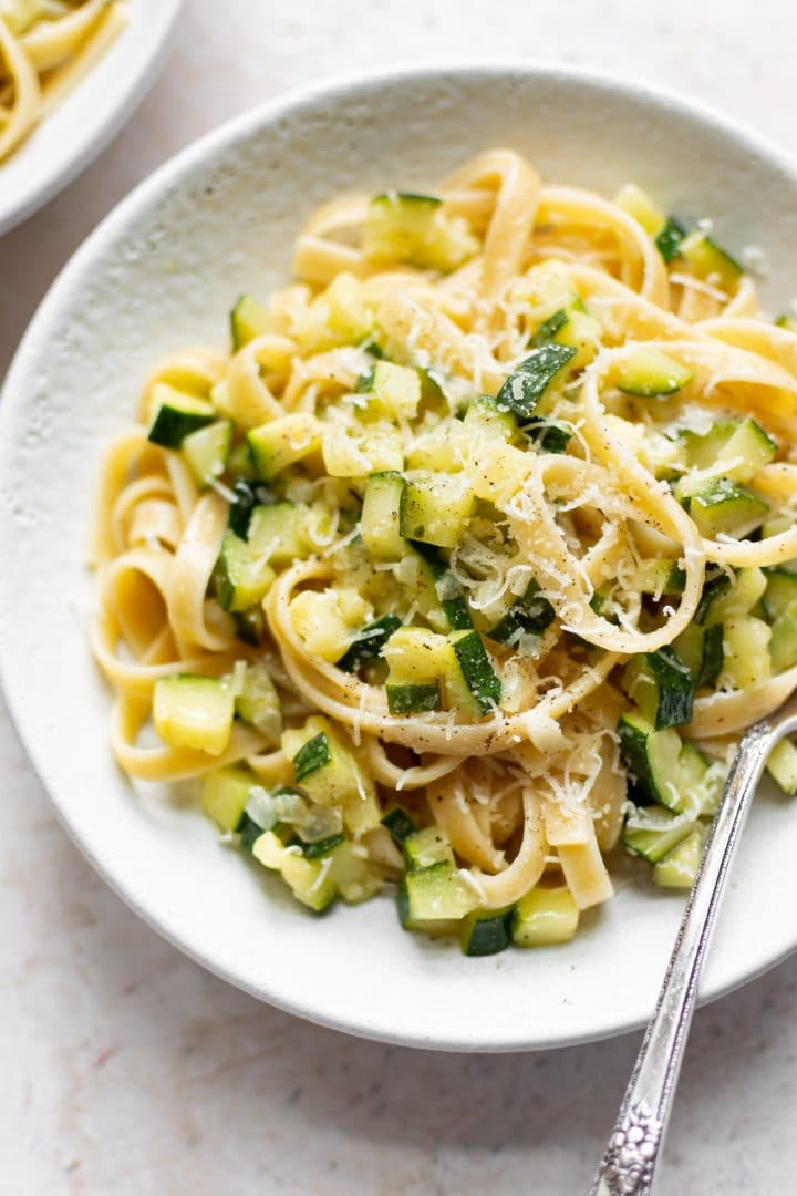 zucchini pasta in a white bowl with fettuccine and a fork