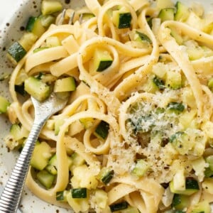 a bowl of pasta with zucchini sauce and a fork