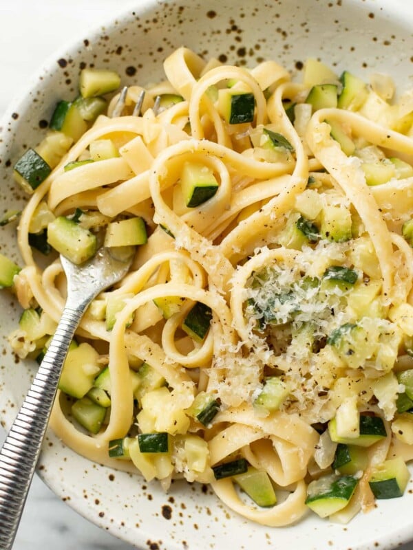 a bowl of pasta with zucchini sauce and a fork