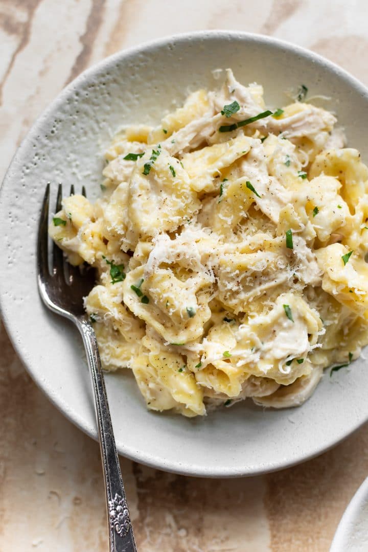 white bowl with chicken tortellini Alfredo and a fork