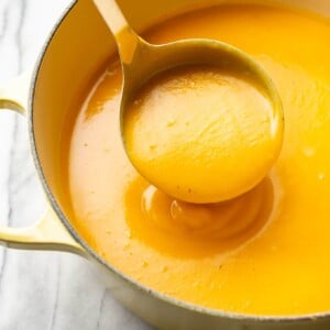 the best butternut squash soup in a yellow soup pot with a ladle full of soup