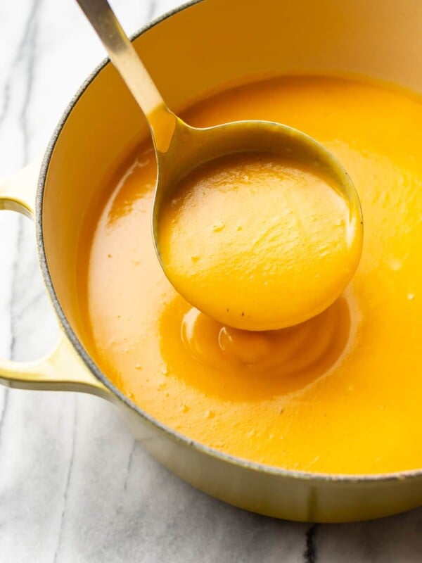 the best butternut squash soup in a yellow soup pot with a ladle full of soup