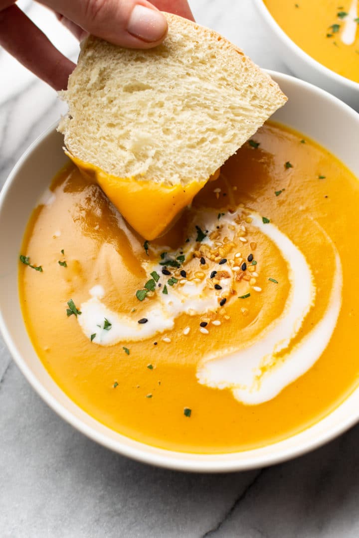 close-up of bread being dipped in a bowl of Instant Pot butternut squash soup