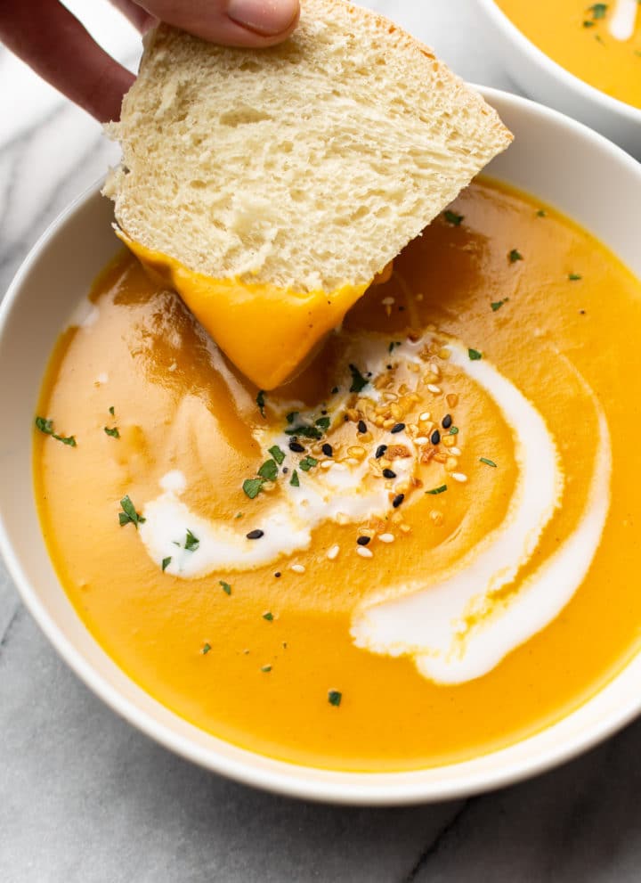 close-up of bread being dipped in a bowl of Instant Pot butternut squash soup