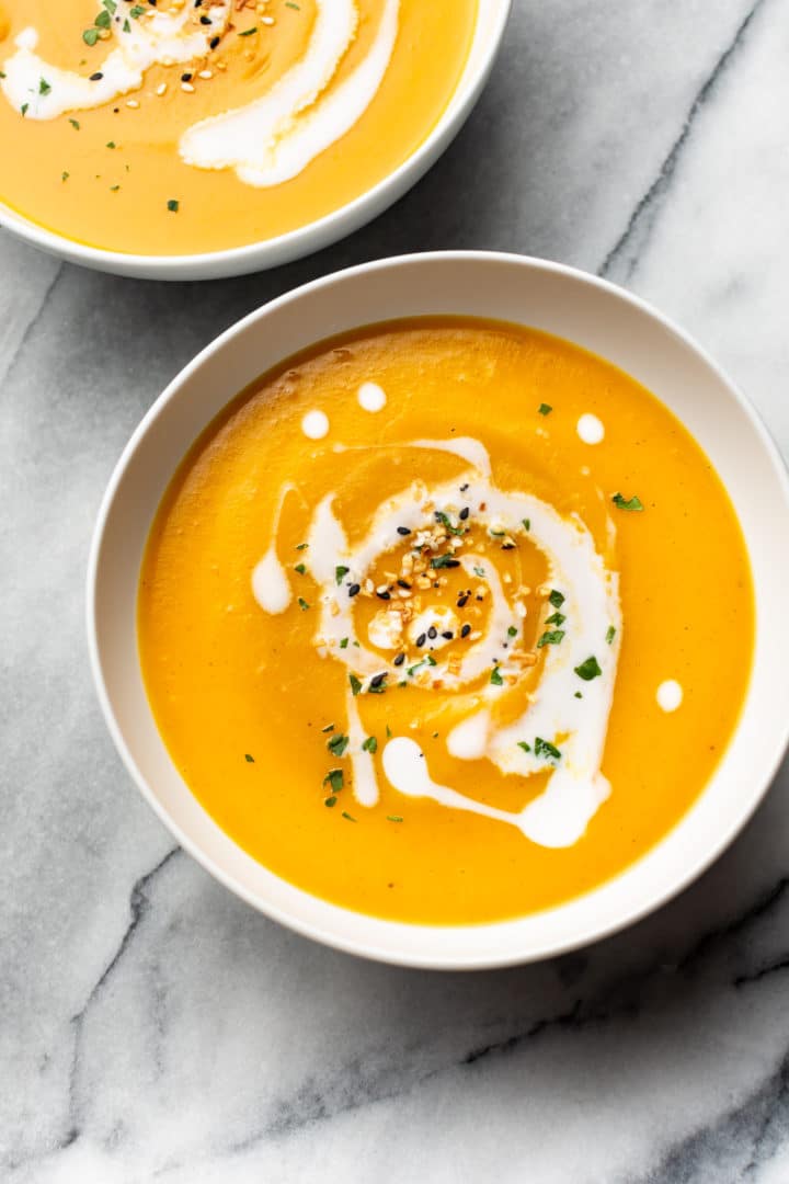 Instant Pot butternut squash soup in two white bowls on marble background