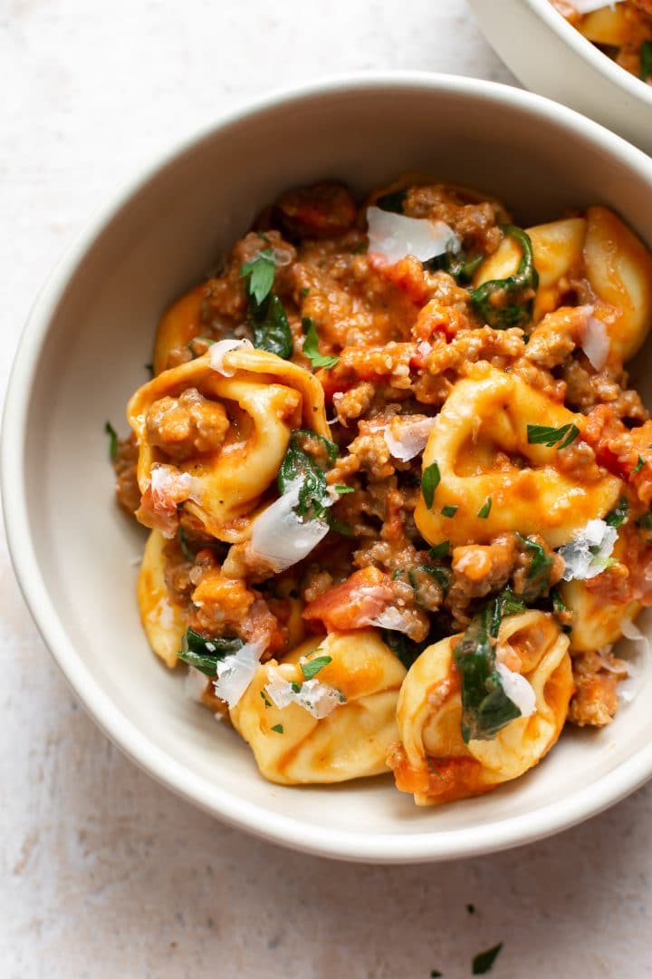 close-up of tortellini with sausage and spinach in a bowl