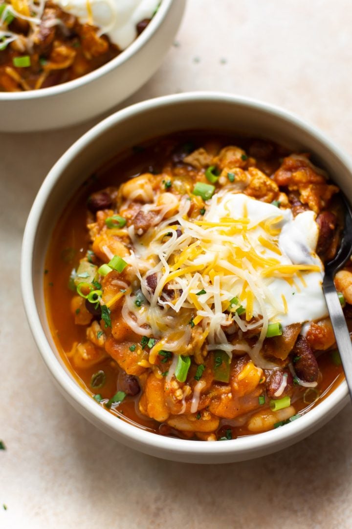 canned pumpkin chili topped with sour cream, cheese, and scallions