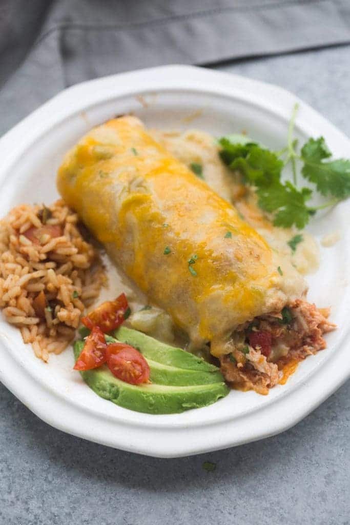 smothered turkey burritos with avocado and rice on a plate