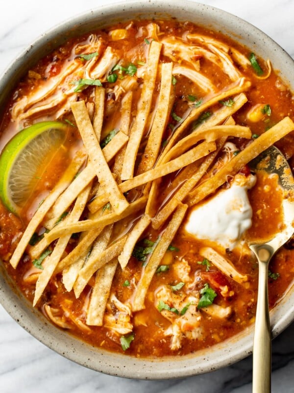 a bowl of chicken tortilla soup with a lime wedge and spoon