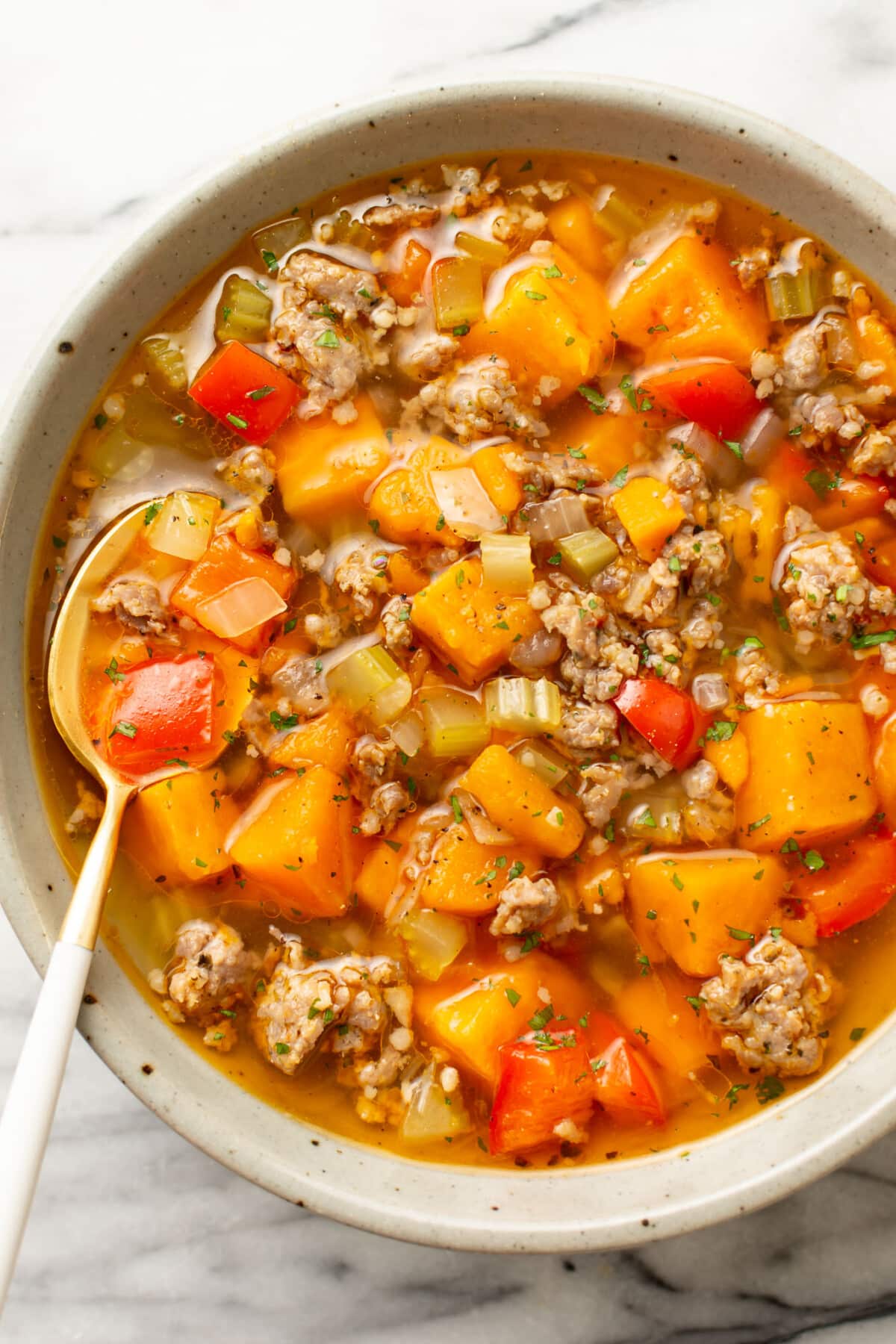 a bowl of italian sausage sweet potato soup with a spoon