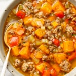 a bowl of italian sausage sweet potato soup with a spoon