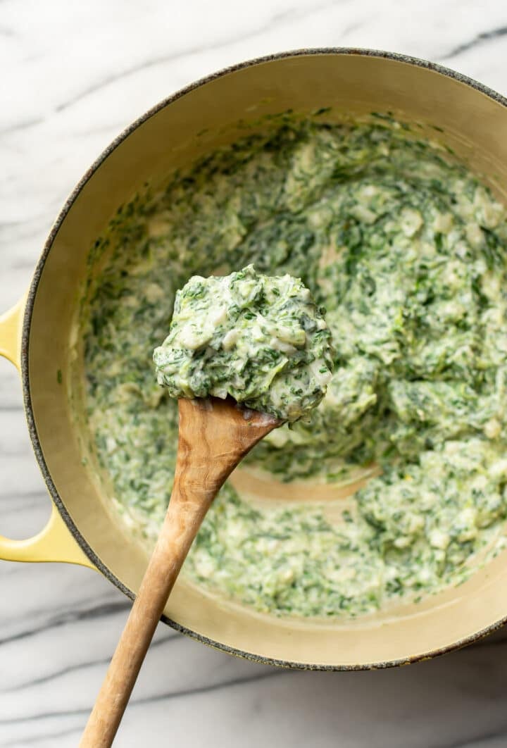 a wooden spoon with creamed spinach