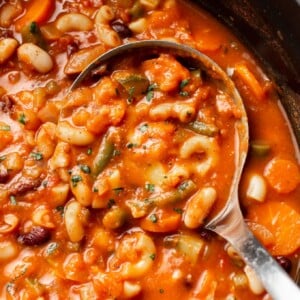 close-up of a ladle in a pot of minestrone soup