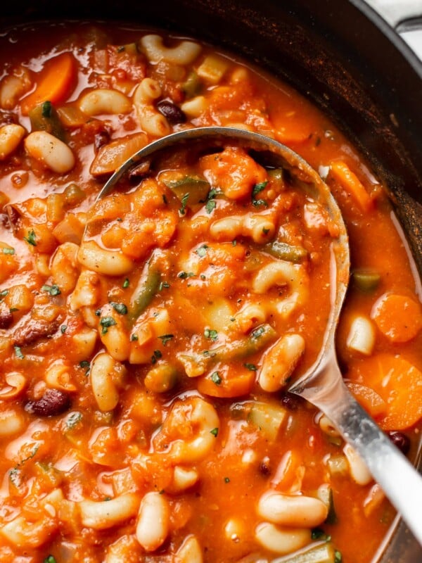 close-up of a ladle in a pot of minestrone soup