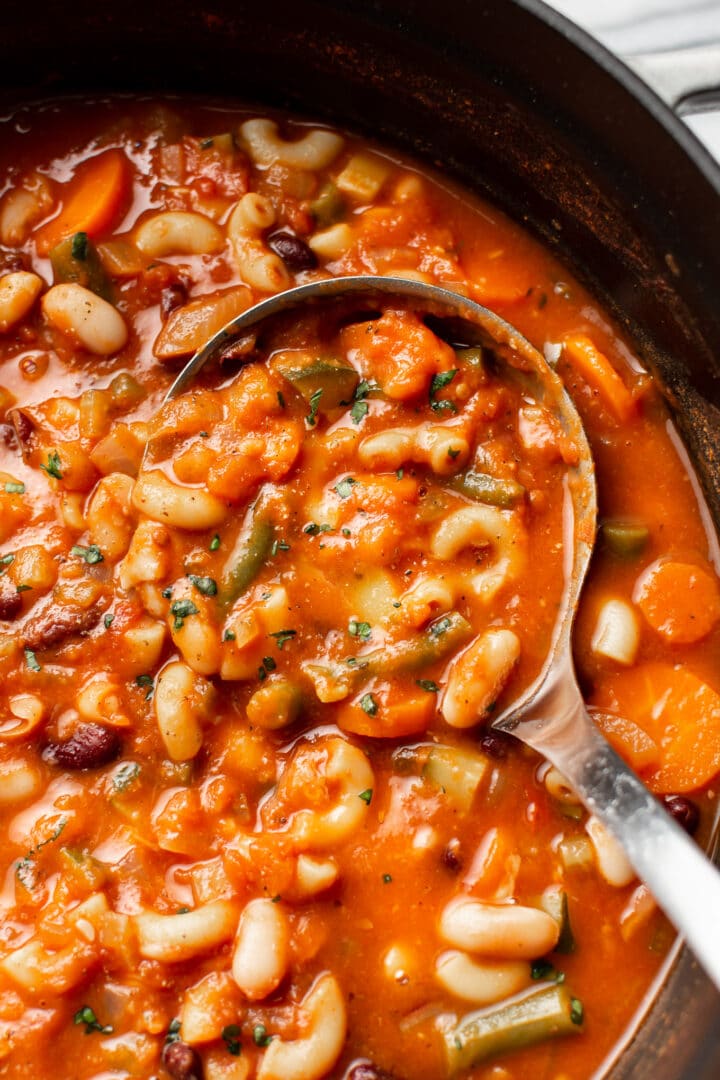 close-up of a ladle in a pot of minestrone soup