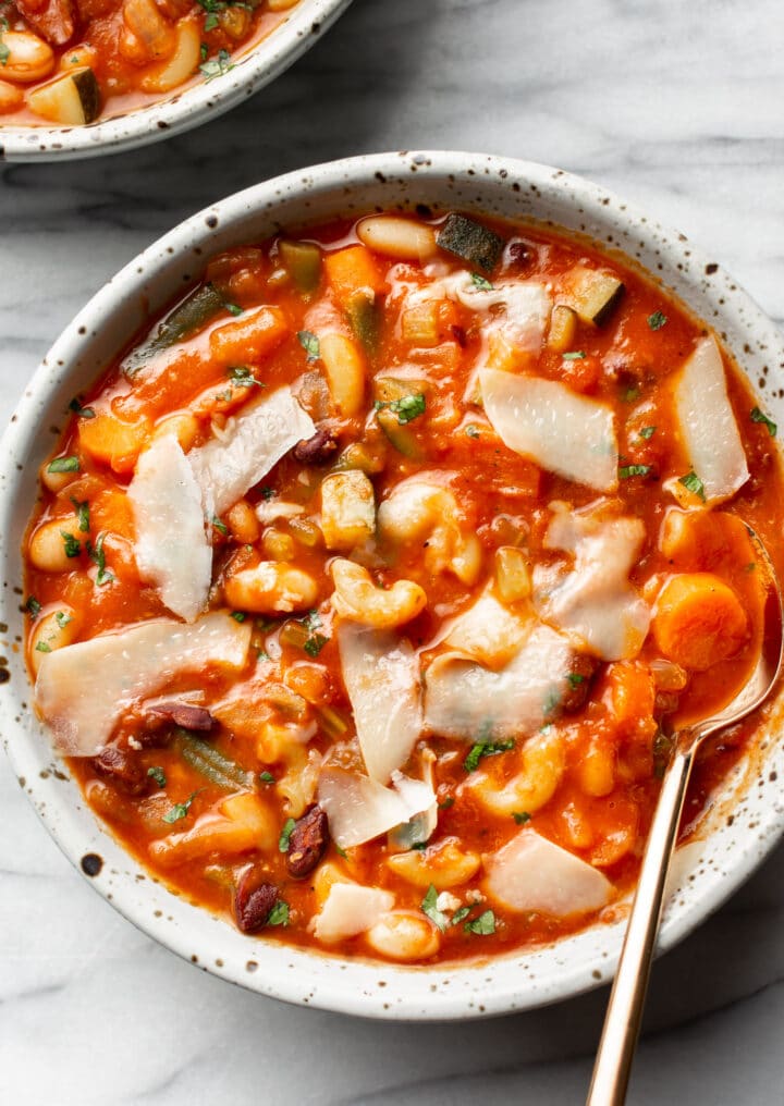 a bowl of minestrone soup with freshly grated parmesan and a spoon