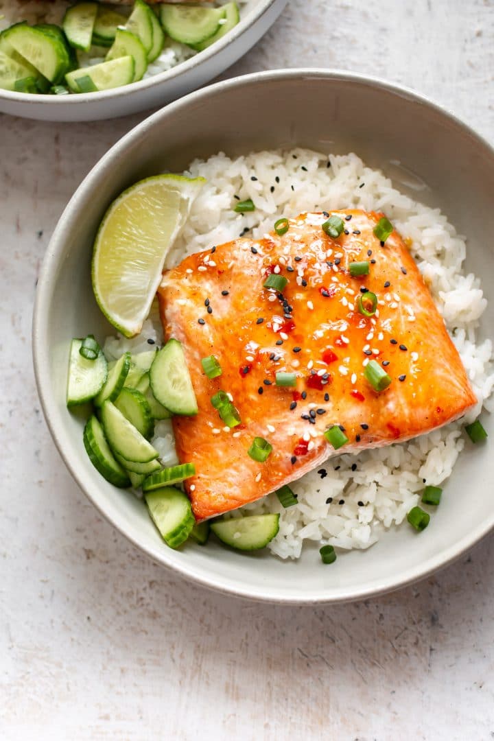 Salmon with sweet chili sauce, rice, lime, cucumber, and scallions in two bowls