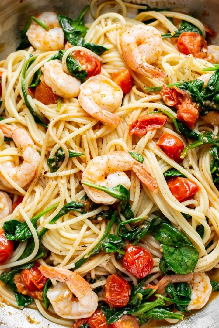 close-up of healthy spinach shrimp pasta with grape tomatoes and garlic