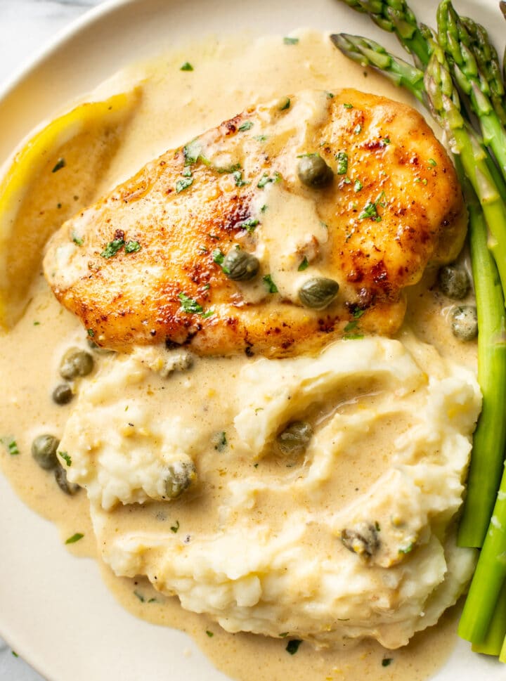 close-up of a plate with chicken piccata, green beans, and mashed potatoes with sauce