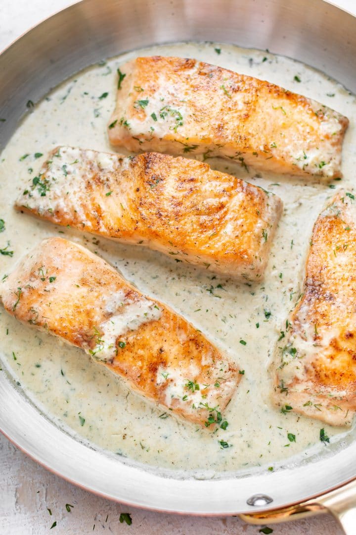 close-up of salmon with creamy lemon dill sauce in a skillet
