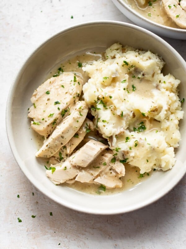 Crockpot chicken and gravy over mashed potatoes in two bowls