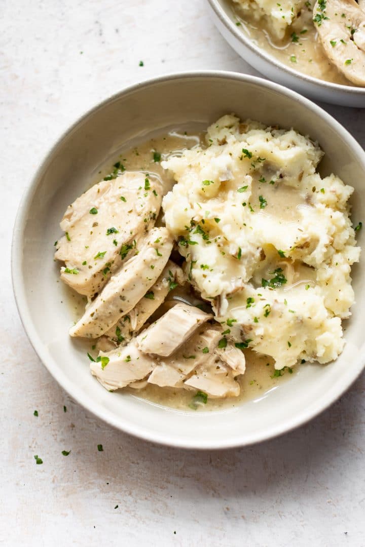 Crockpot chicken and gravy over mashed potatoes in two bowls