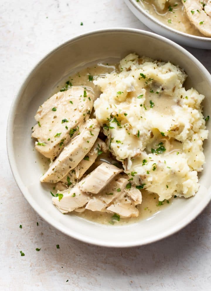 Crockpot chicken and gravy over mashed potatoes in two bowls