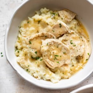 Instant Pot chicken and gravy with mashed potatoes in two white bowls