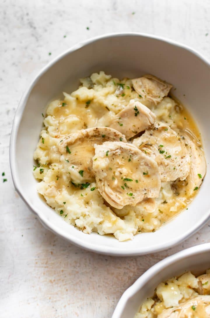 Instant Pot chicken and gravy with mashed potatoes in two white bowls