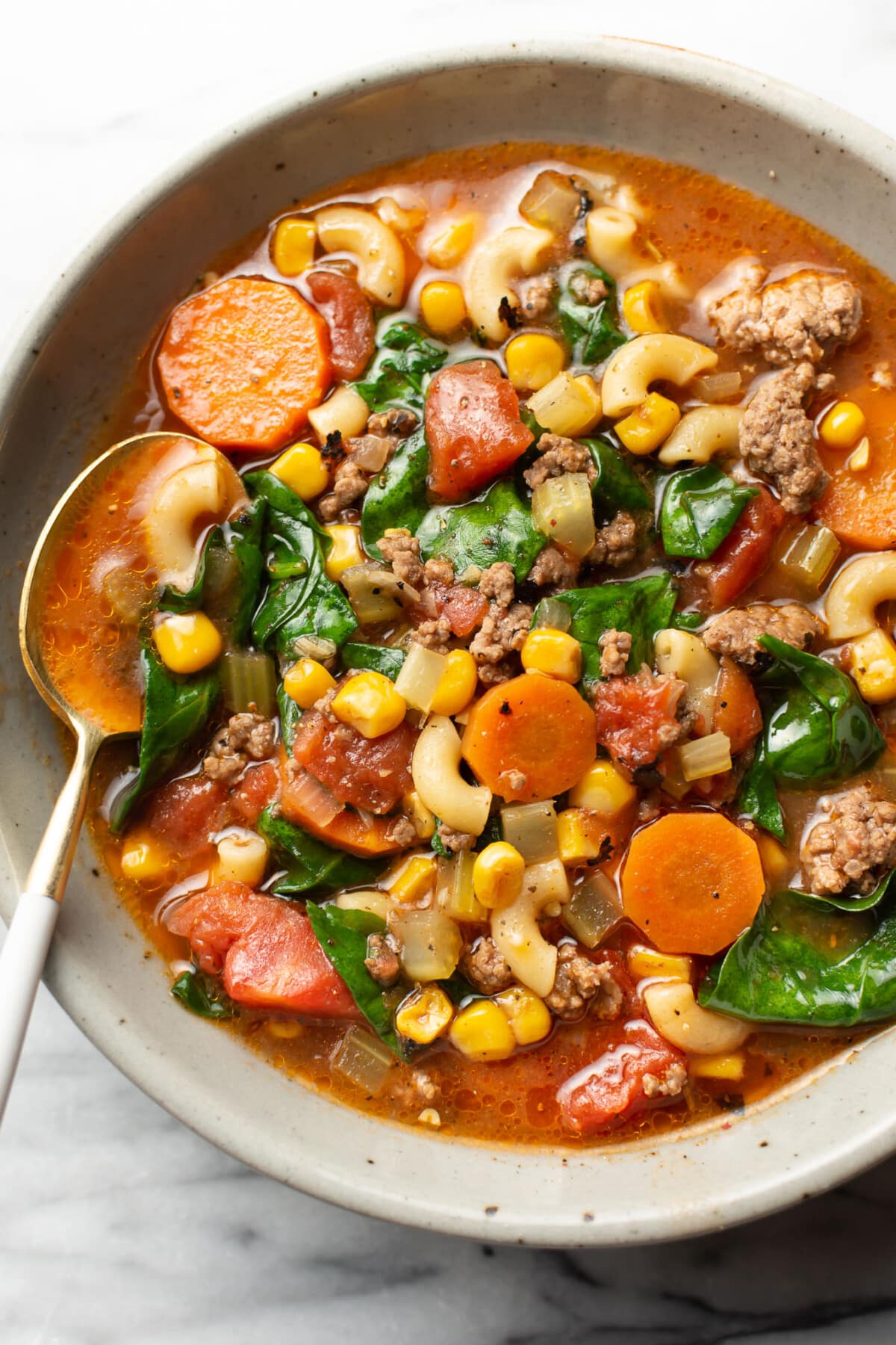 a bowl of ground beef macaroni soup with a spoon