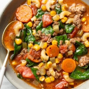 a bowl of ground beef macaroni soup with a spoon