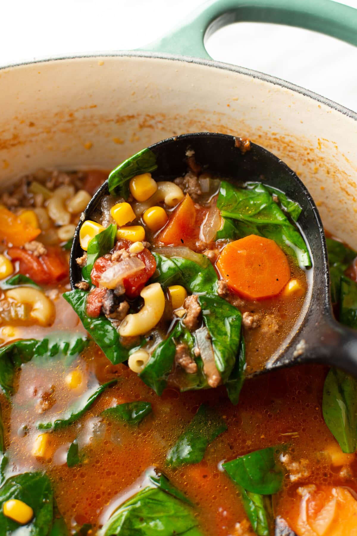 a soup pot with macaroni soup and a ladle