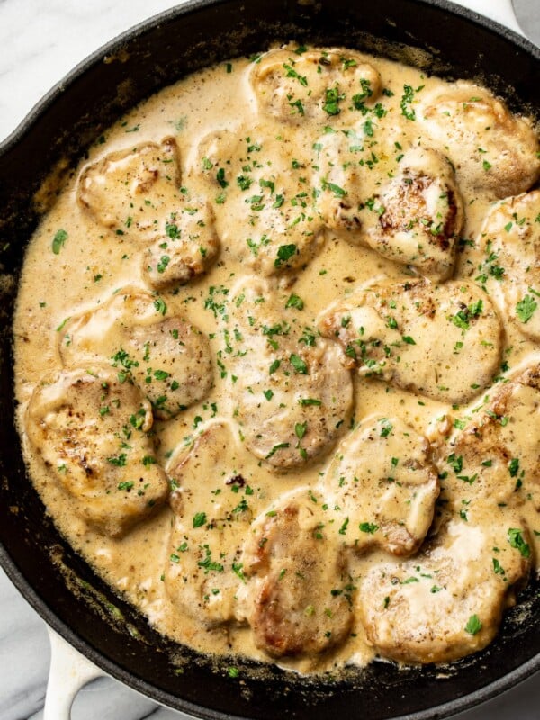 a cast iron skillet with pork tenderloin medallions in a creamy sauce