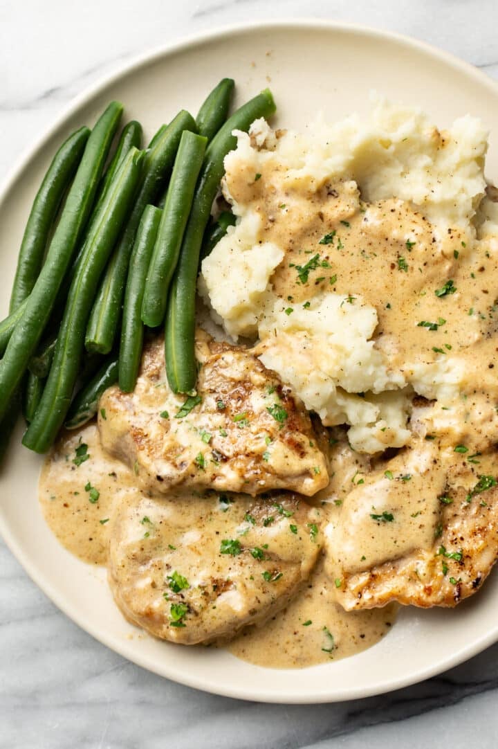 a plate with creamy pork tenderloin, mashed potatoes, and green beans