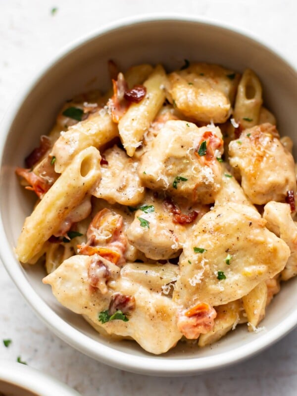 creamy chicken penne with fresh tomatoes and bacon in a white bowl