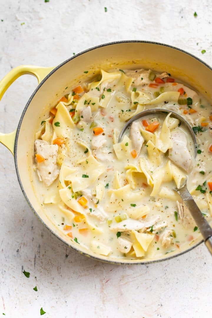 creamy chicken noodle soup in a yellow Le Creuset pot