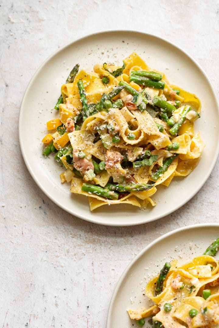 two plates of creamy pasta primavera