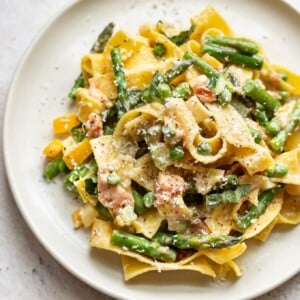 close-up of creamy pasta primavera on a beige plate