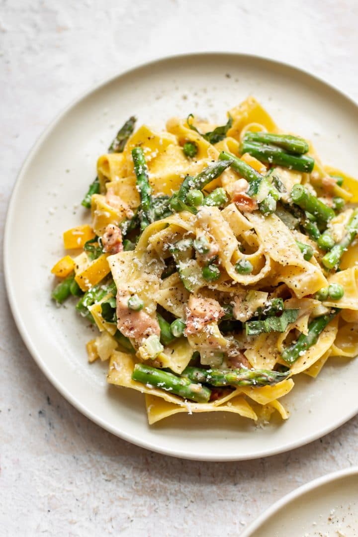 close-up of creamy pasta primavera on a beige plate