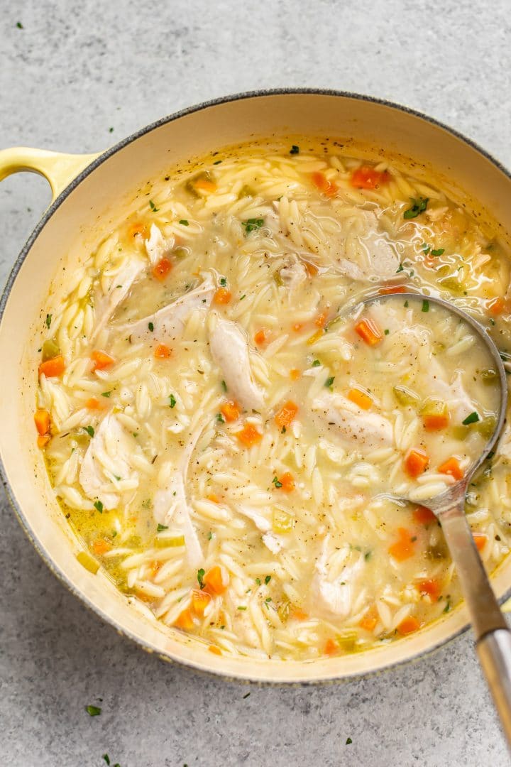 close-up of lemon chicken orzo soup in a yellow pot