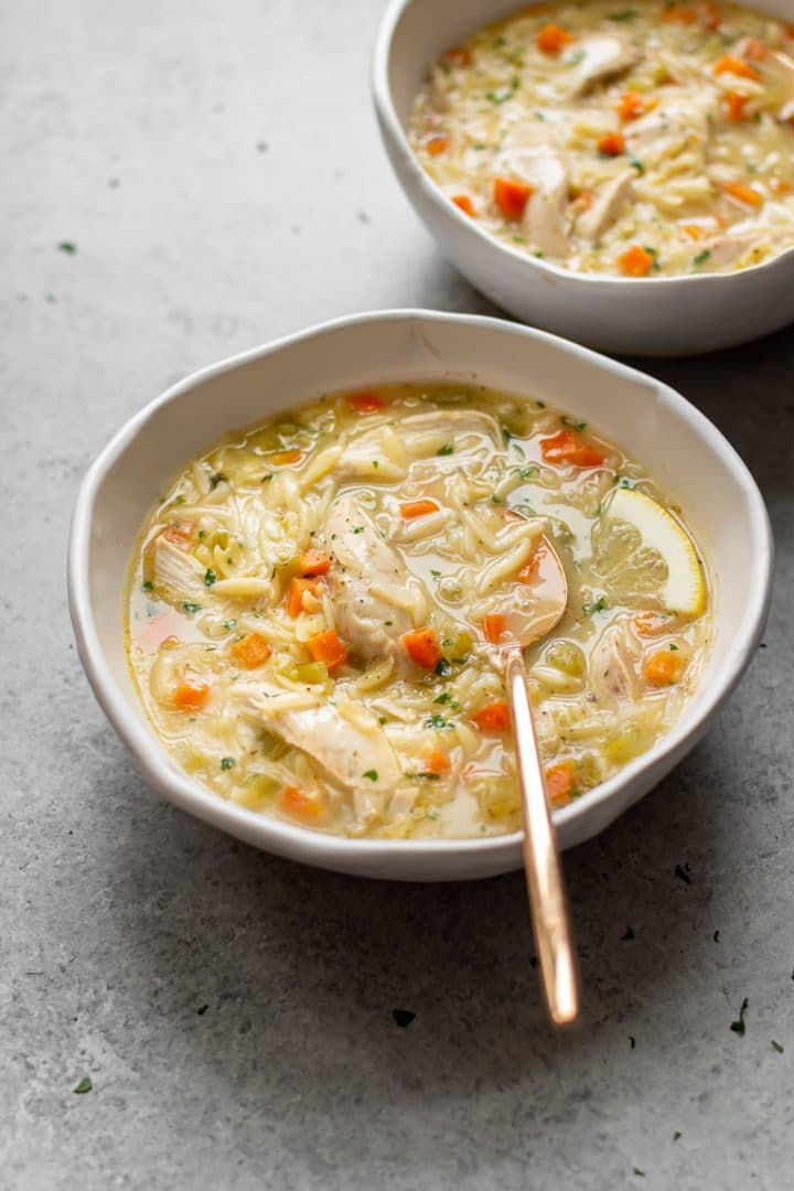 healthy lemon chicken orzo soup in two white bowls