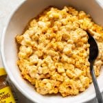 elote cream cheese corn in a white bowl with a serving spoon