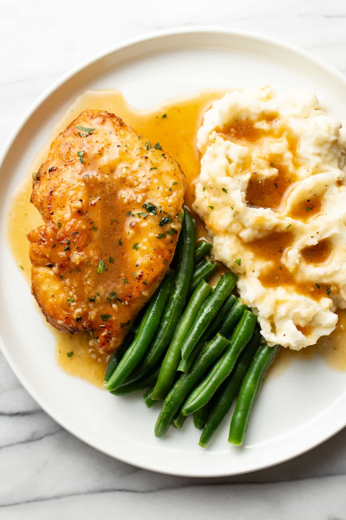 a plate with honey soy sauce chicken, mashed potatoes, and green beans