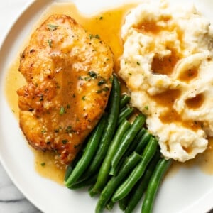 a plate with honey soy sauce chicken, mashed potatoes, and green beans
