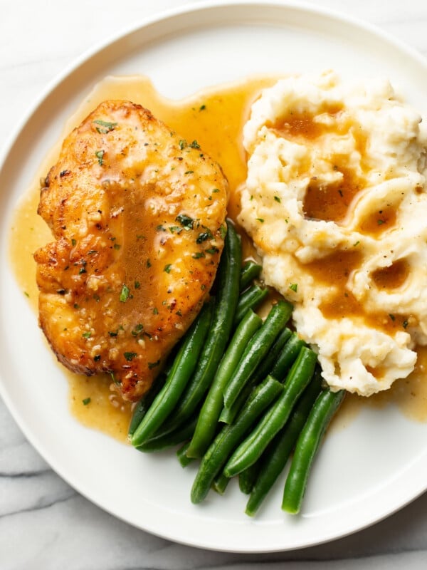 a plate with honey soy sauce chicken, mashed potatoes, and green beans