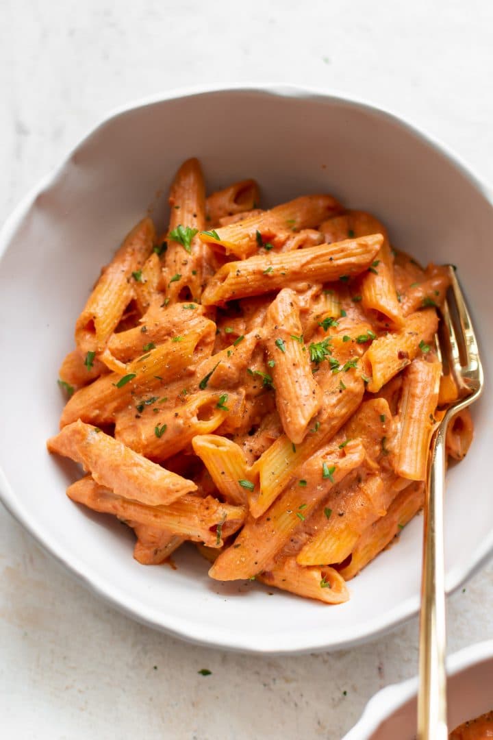tomato and goat cheese penne close-up with a gold fork