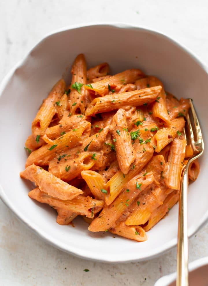 tomato and goat cheese penne close-up with a gold fork